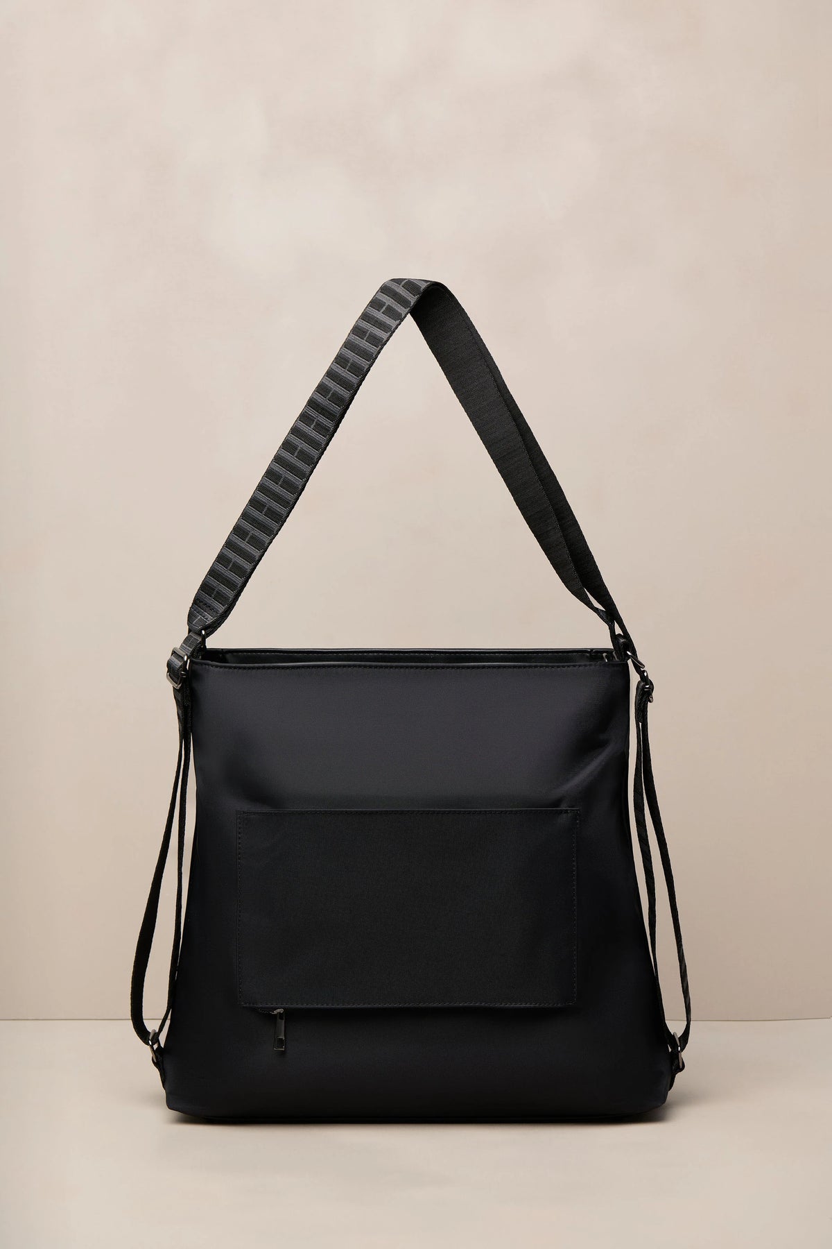 A black nylon shoulder bag with a wide, textured black-and-gray striped strap, shown against a neutral beige background.