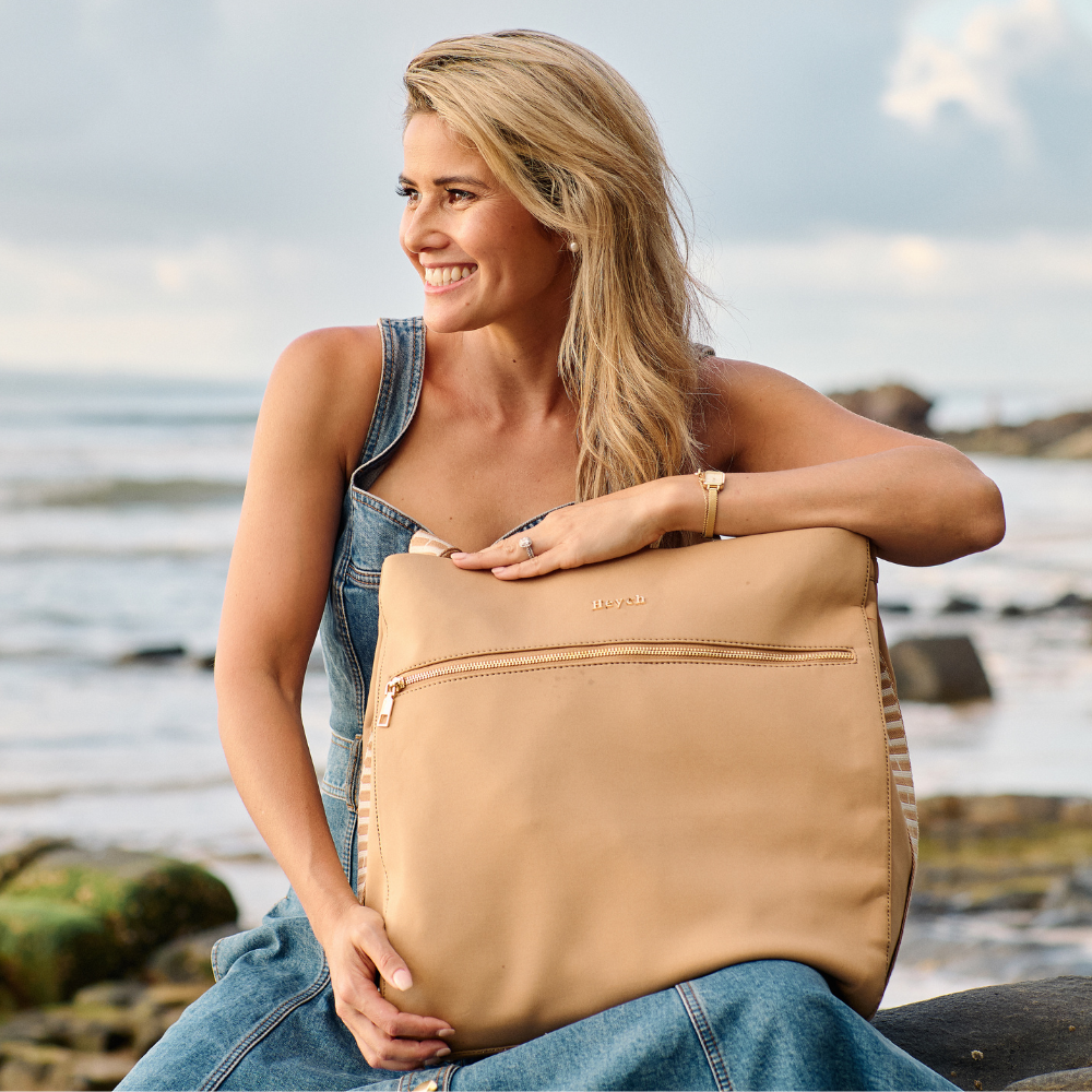 Founder Laura King holding a Heiych bag by the sea
